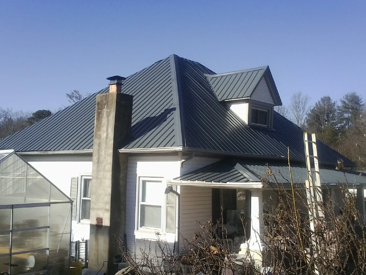 Dark blue standing seam metal roof on a white farmhouse with dormer — Slate & Tile Roof Repair by Roofing Brothers in Winchester
